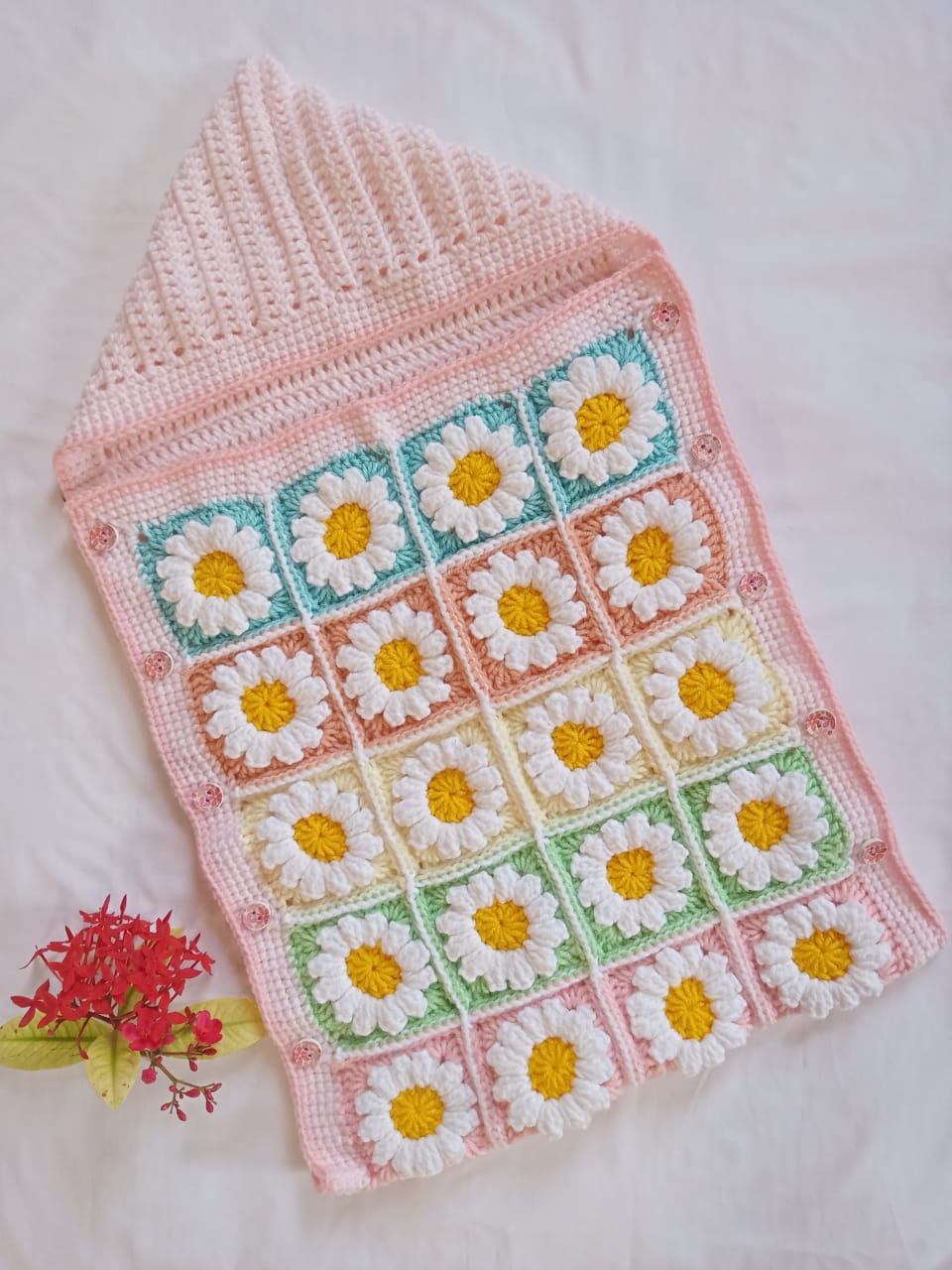 Handmade crochet baby sleeping bag with daisy granny square pattern in pink and multicolor
