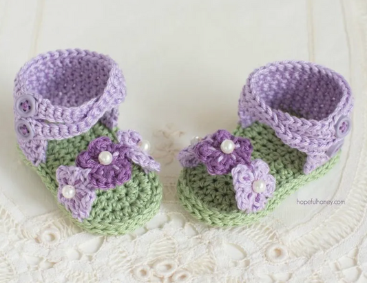Green and purple crochet baby booties with purple flowers