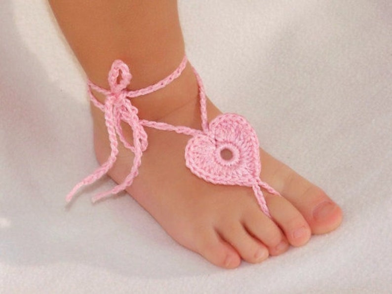 Baby pink crochet barefoot heart sandals with ankle ties on baby feet