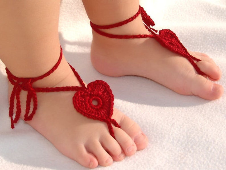 Red crochet barefoot heart sandals with ankle ties on baby feet