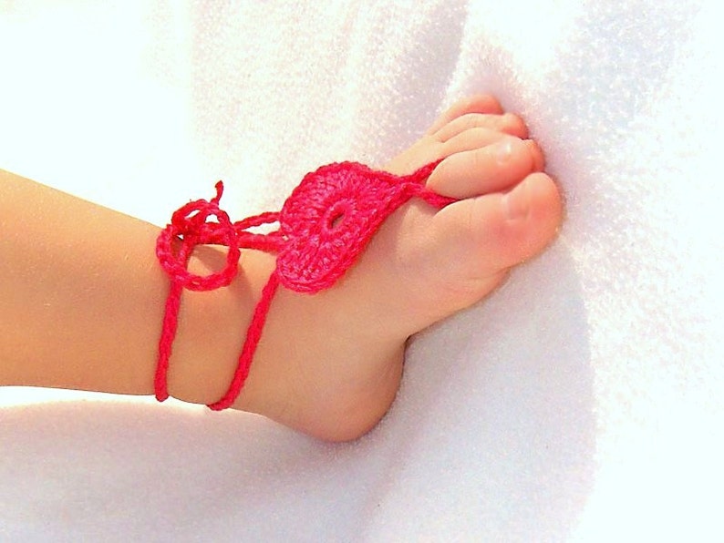 Shocking pink crochet barefoot heart sandals on baby feet