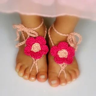 Pink crochet barefoot baby daisy flower sandals with peach centre on baby feet