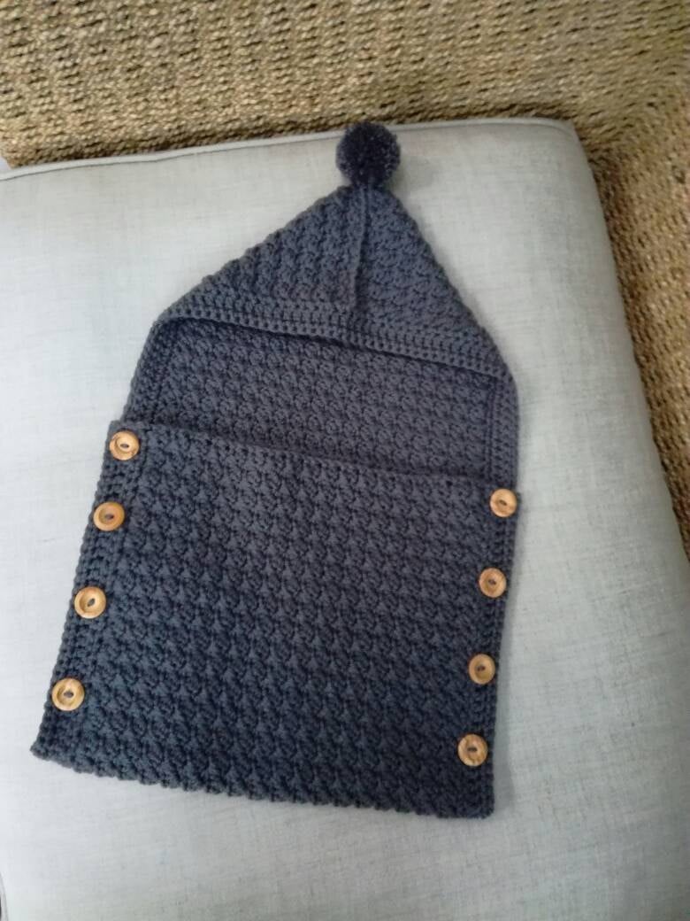 Handmade crochet baby cocoon in grey with wooden button detail and pom pom hood
