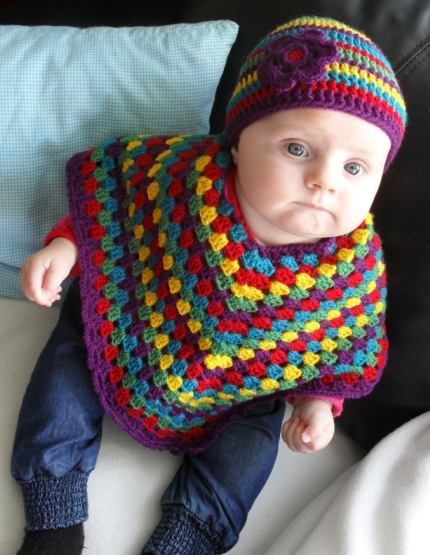 Baby wearing a handmade crochet rainbow multicolor poncho and matching hat
