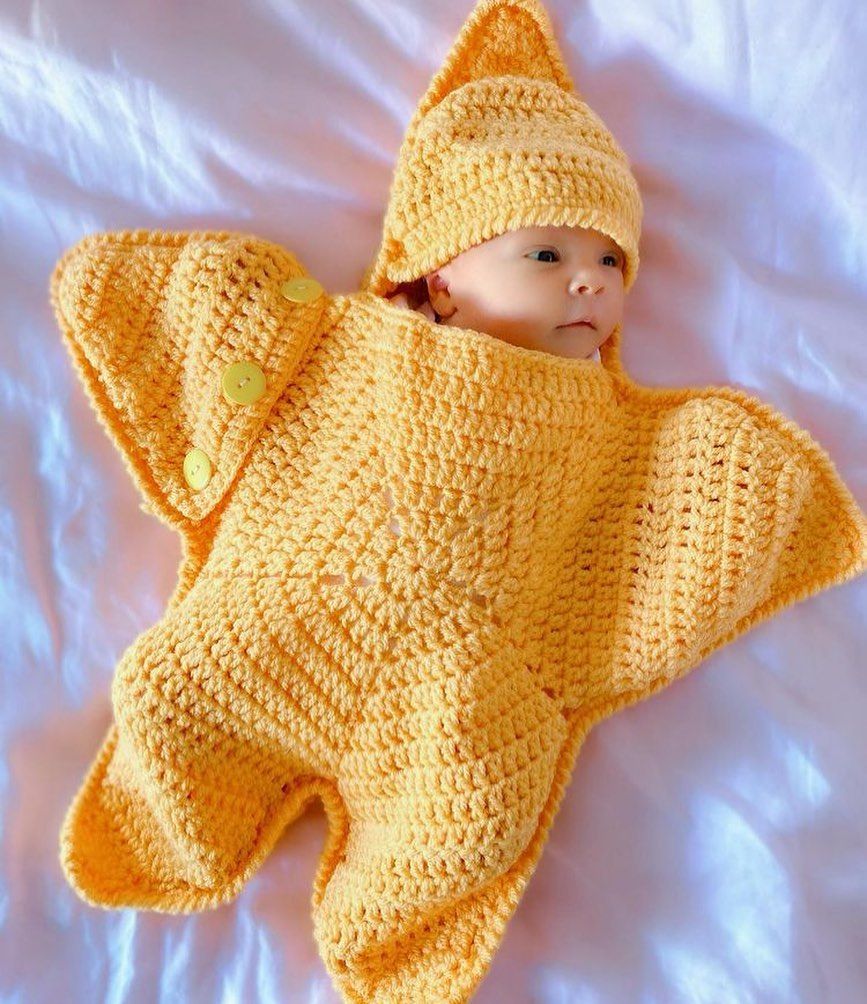 Newborn baby in a handmade crochet yellow starfish shaped cocoon and hat set