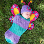 Newborn baby wrapped in a handmade crochet butterfly cocoon and hat set in purple and teal
